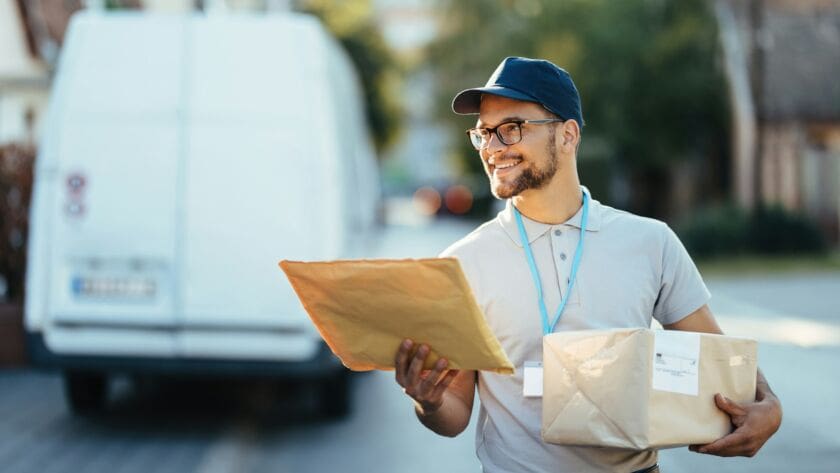 Young happy courier making a delivery in the city.